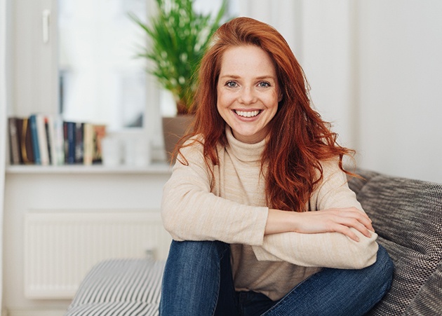Woman with red hair sitting on couch and smiling