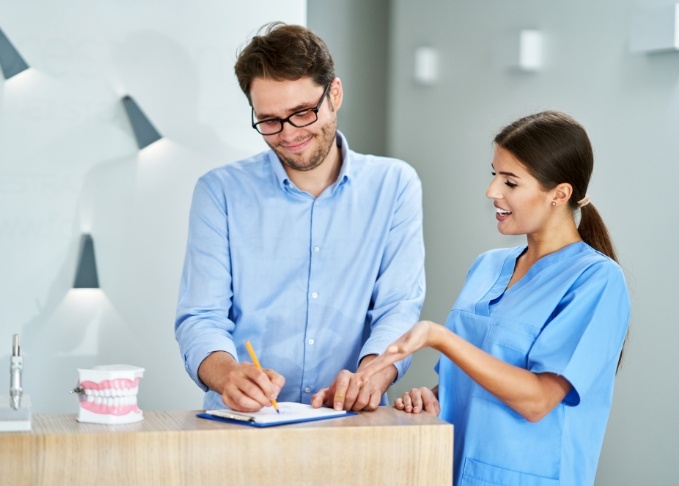Dental team member showing a clipboard to a patient in Bedford dental office
