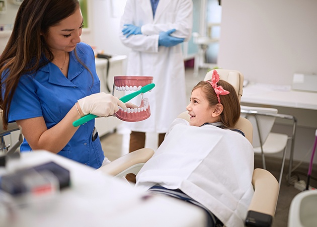 Dentist in white coat examining little boy’s teeth