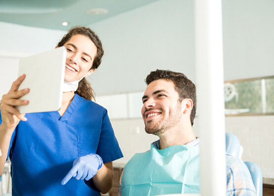 dentist showing patient image on tablet