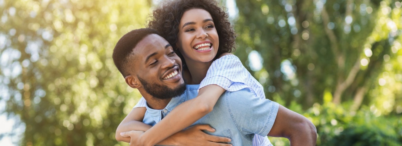 Man and woman laughing outdoors after dental services in Bedford