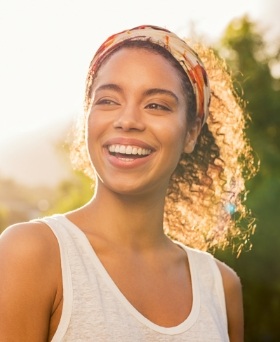 Woman with curly hair grinning outdoors