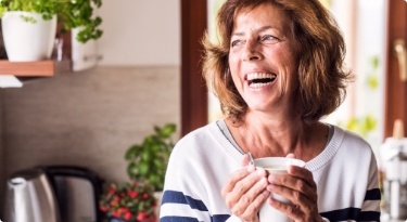 Senior woman laughing while holding coffee cup