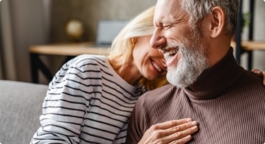 Laughing senior man and woman holding each other
