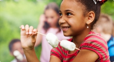 Young girl holding marshmallow on stick