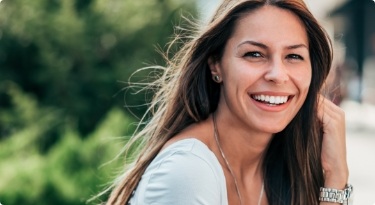 Woman with long brown hair smiling outdoors