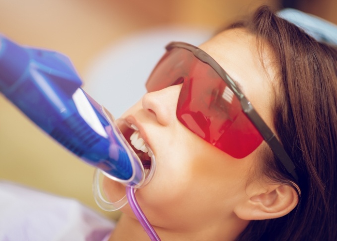 Girl in dental chair with fluoride trays on her teeth